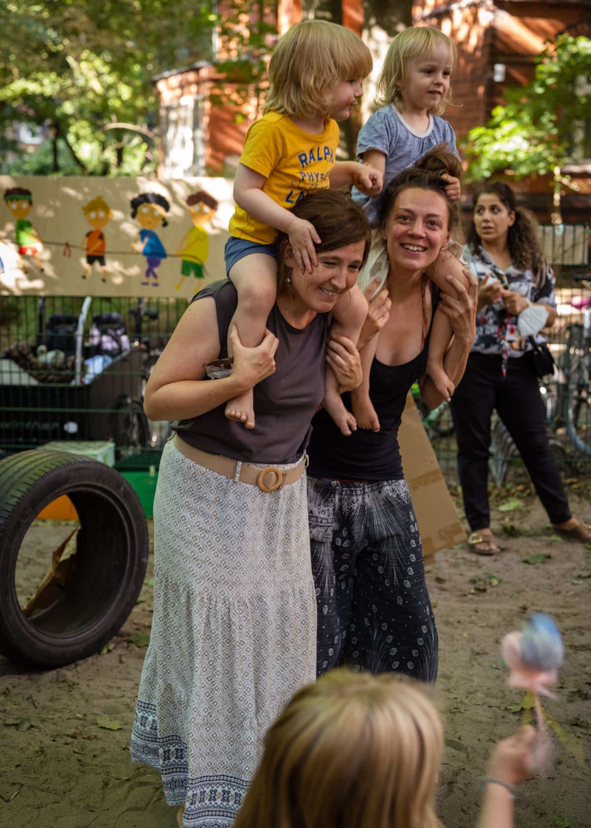 Zwei Frauen mit Kindern auf ihren Schultern auf einem Spielplatz